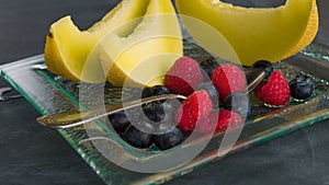 Fresh healthy fruit on a glass dessert plate on black background. Healthy eating concept