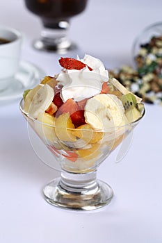 Fresh healthy fruit salad in a glass with whipping cream