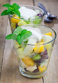 Fresh healthy fruit salad in a glass with whipping cream