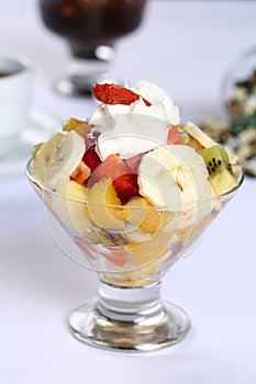 Fresh healthy fruit salad in a glass with whipping cream