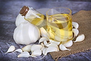 Fresh healthy garlic oil on the wooden background