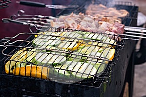 Fresh healthy green zucchini courgettes cucumber preparing on a barbecue grill over charcoal. Grilled zucchini slices. Vegetarian,