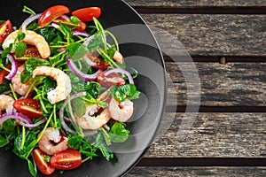 Fresh Healthy Prawns salad with tomatoes, red onion on black plate. concept healthy food