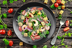 Fresh Healthy Prawns salad with tomatoes, red onion on black plate. concept healthy food