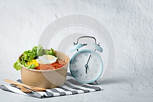 Fresh healthy salad with an alarm clock