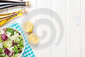 Fresh healthy salad and condiments over white wooden table