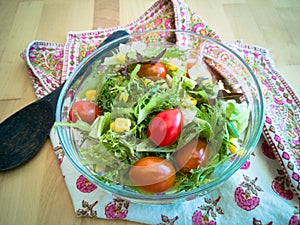 A fresh and healthy salad made with fruits and vegetables in a bowl on a wooden background.