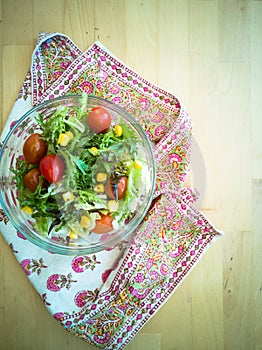 A fresh and healthy salad made with fruits and vegetables in a bowl on a wooden background.