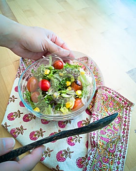 A fresh and healthy salad made with fruits and vegetables in a bowl on a wooden background.