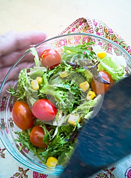 A fresh and healthy salad made with fruits and vegetables in a bowl on a wooden background.