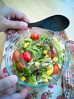 A fresh and healthy salad made with fruits and vegetables in a bowl on a wooden background.