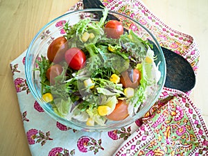 A fresh and healthy salad made with fruits and vegetables in a bowl on a wooden background.