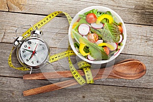 Fresh healthy salad and measuring tape on wooden table