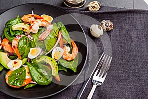 Fresh, healthy salad with shrimps, spinach and avocado on a black background. Top view.