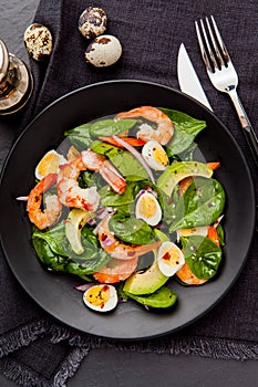 Fresh, healthy salad with shrimps, spinach and avocado on a black background. Top view.