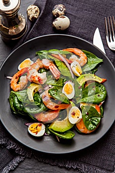 Fresh, healthy salad with shrimps, spinach and avocado on a black background. Top view.