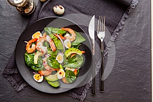 Fresh, healthy salad with shrimps, spinach and avocado on a black background. Top view.