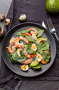 Fresh, healthy salad with shrimps, spinach and avocado on a black background. Top view.