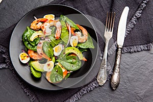 Fresh, healthy salad with shrimps, spinach and avocado on a black background. Top view.