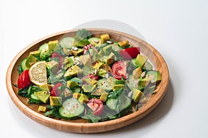 Fresh and healthy summer salad with cucumbers, tomatoes, avocado, arugula, sunflower seeds, lemons and chili flakes.