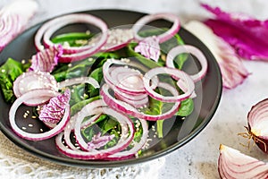 Fresh healthy vitamin salad. Salad of red onion, spinach and blue Chinese cabbage, seasoned with olive oil and sesame seeds. Close