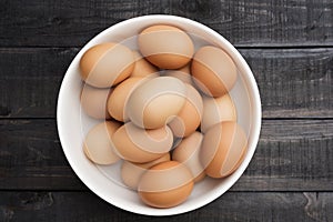 Fresh hen egg in white bowl on Black color wood table