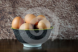 Fresh Hens Eggs in a Coloured Bowl on a Wooden Table Top