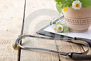 Fresh herb, medical clipboard and stethoscope on wooden table. Alternative medicine concept.