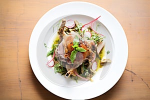 fresh herbs scattered around a plate of duck confit