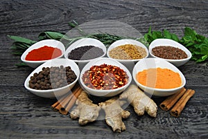 Fresh herbs and spices in dishes with on a rustic wood background, diagonal view