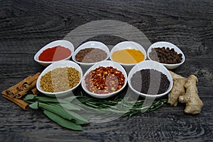 Fresh herbs and spices in dishes with on a rustic wood background, diagonal view photo