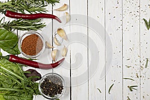 Fresh herbs, spices in glass bowls on a white wooden background. Top view