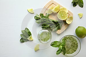 Fresh home-made lemonade with lemon, lime and mint in a glass on white background and ingredients laying on the table