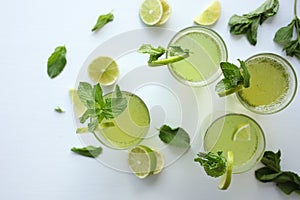 Fresh home-made lemonade with lemon, lime and mint in a glass on white background and ingredients laying on the table