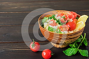 Fresh home-made tabouli, or tabbouleh salad, side view on dark wooden background, copy space