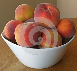 Fresh homegrown peaches heaped in a white bowl