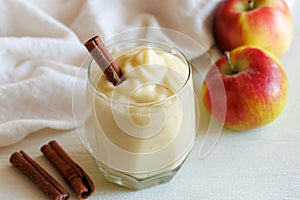 Fresh homemade applesauce, apple puree, mousse, sauce in glass with cinnamon and apples on white table, side view