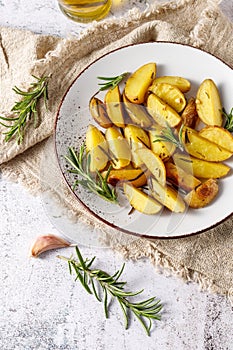 Fresh homemade baked potatoes with olive oil, rosemary and garlic on vintage plate over linen towel