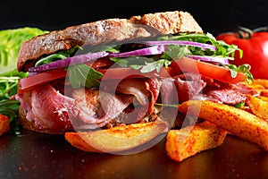Fresh homemade BLT sandwich on grilled bread with bacon, lettuce, beef tomato, red onions, wild rocket and chips