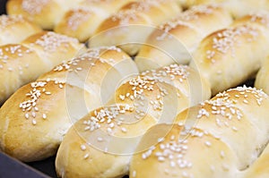 Fresh homemade bread rolls with sesam seed in basket on wooden t