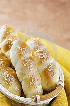 Fresh homemade bread rolls with sesam seed in basket on wooden t