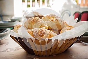 Fresh homemade bread rolls with sesam seed in basket on wooden t