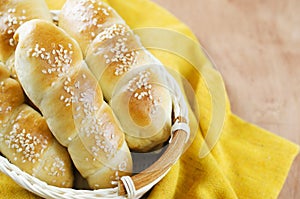 Fresh homemade bread rolls with sesam seed in basket on wooden t