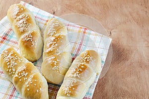 Fresh homemade bread rolls with sesam seed on napkin on wooden t