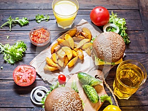 Fresh homemade burgers, fried potatoes, beer and juice served on wood table