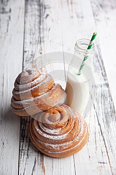 Fresh homemade cinnamon rolls on a wooden cutting desk and milk in glass bottle