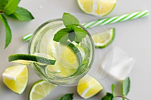 Fresh homemade cocktail with lime, mint and ice on a white table, close up, top view