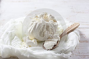 Fresh homemade cottage cheese in cheesecloth on white wooden ta