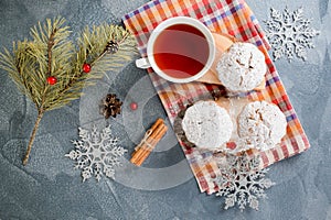 Fresh homemade cranberry muffins in icing sugar with fir-tree branches and tea.