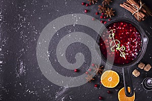 Fresh homemade cranberry sauce in a pan on dark wooden background with scattering of ripe berries.